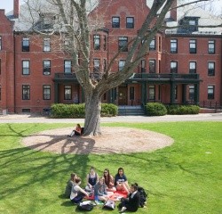Students sitting on Skinner Green with Wilder Hall in the background