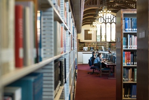 Two students working at a long table in the library.