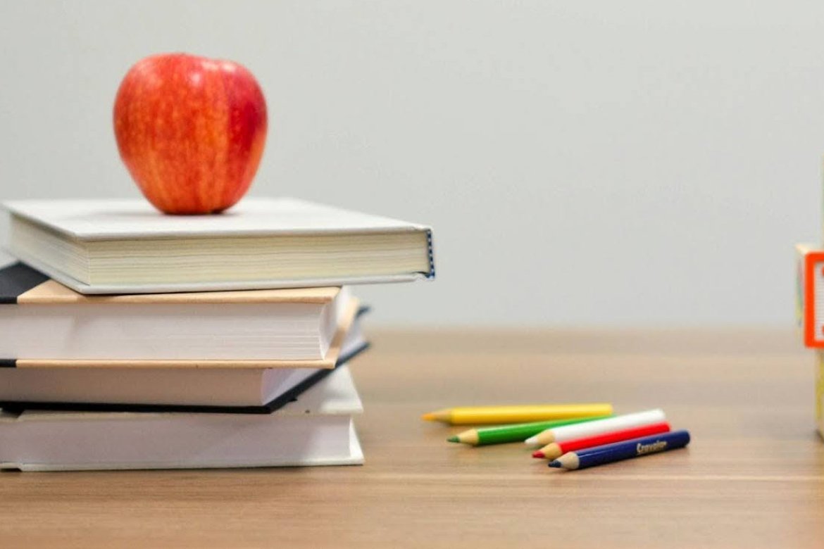 Teacher’s desk with books, blocks, colored pencils and an apple.