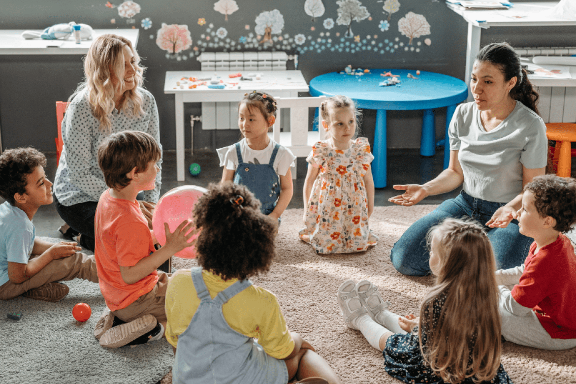 Young students sitting in a circle with teachers.