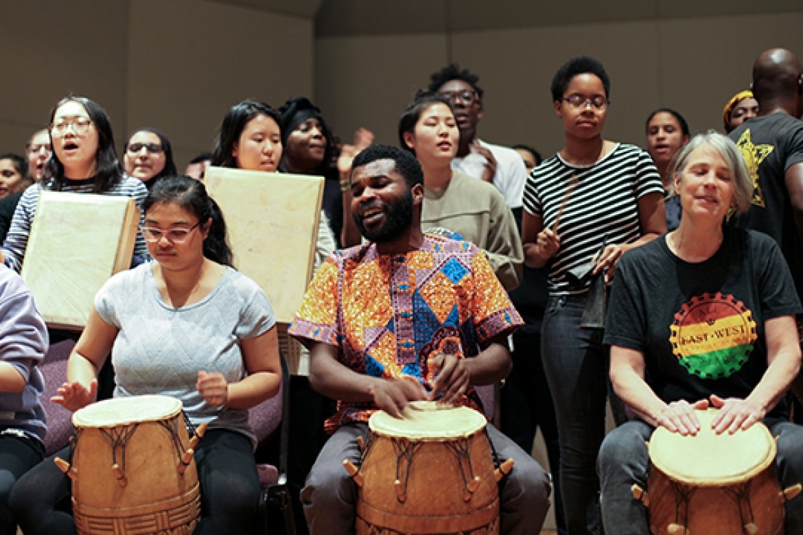 Michael Ofori, center right, and Faith Conant, right, drum with students as part of the final drumming, dancing and singing performance of their classes.