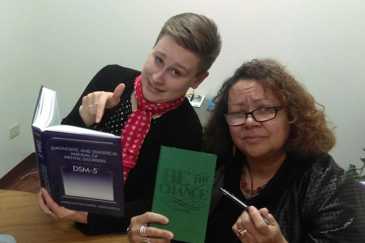 Megan Brookman with her supervisor holding a “Be the Change” sign. Image courtesy of Megan Brookman ‘14.