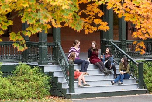 A group of Mount Holyoke College students sitting on some steps talking