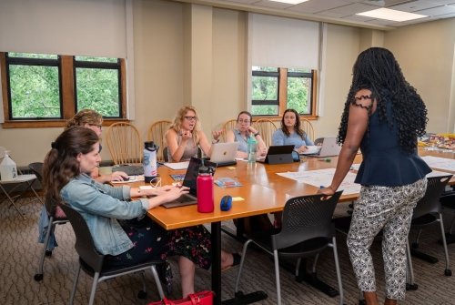 Social-emotional learning for districts and schools - a small group gathered around a table engaged in discussion.