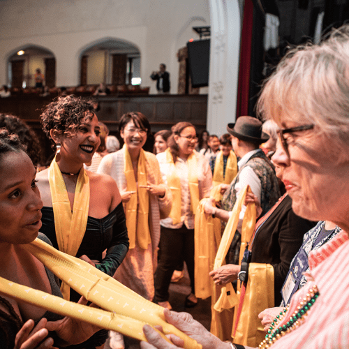 An alum presenting a scarf to a graduating senior in their class color