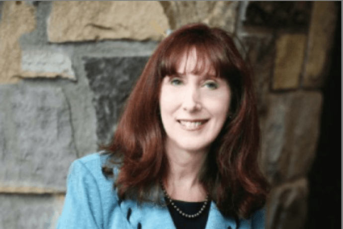 Katherine Bassett, wearing a blue jacket in front of a stone wall.