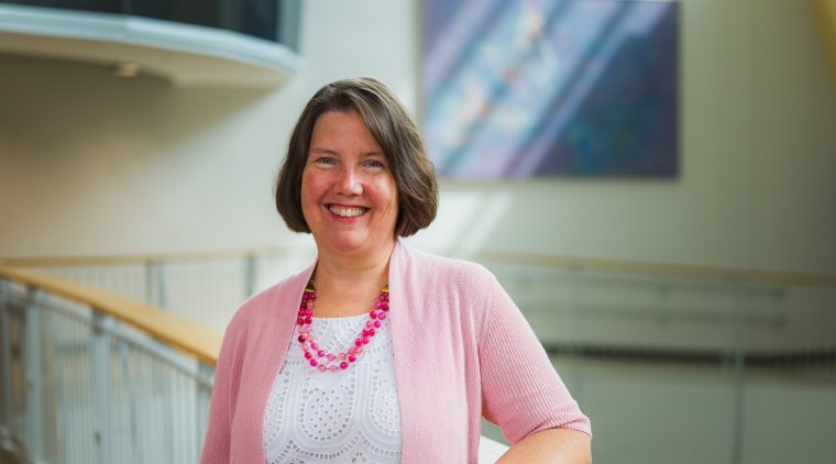 Dana Gillette, a woman wearing pink and smiling with brown hair.