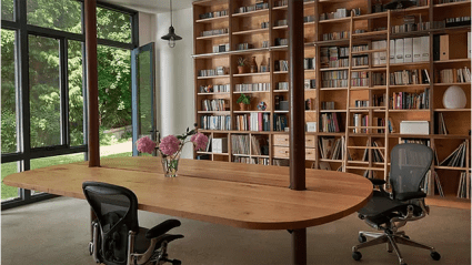 Another view of Darling’s redesigned garage. Floor-to-ceiling bookshelves in light-colored wood line one wall, while large windows connect to the green space beyond.