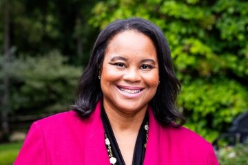 Danielle R. Holley, President of Mount Holyoke College in pink with green trees in the background.