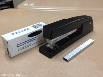 Photo from estimation180.com - a photo of a black stapler, with a stripe of staples next to it for estimation